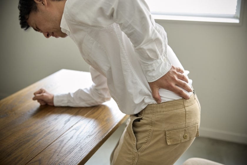 A man suffers from back pain at work.